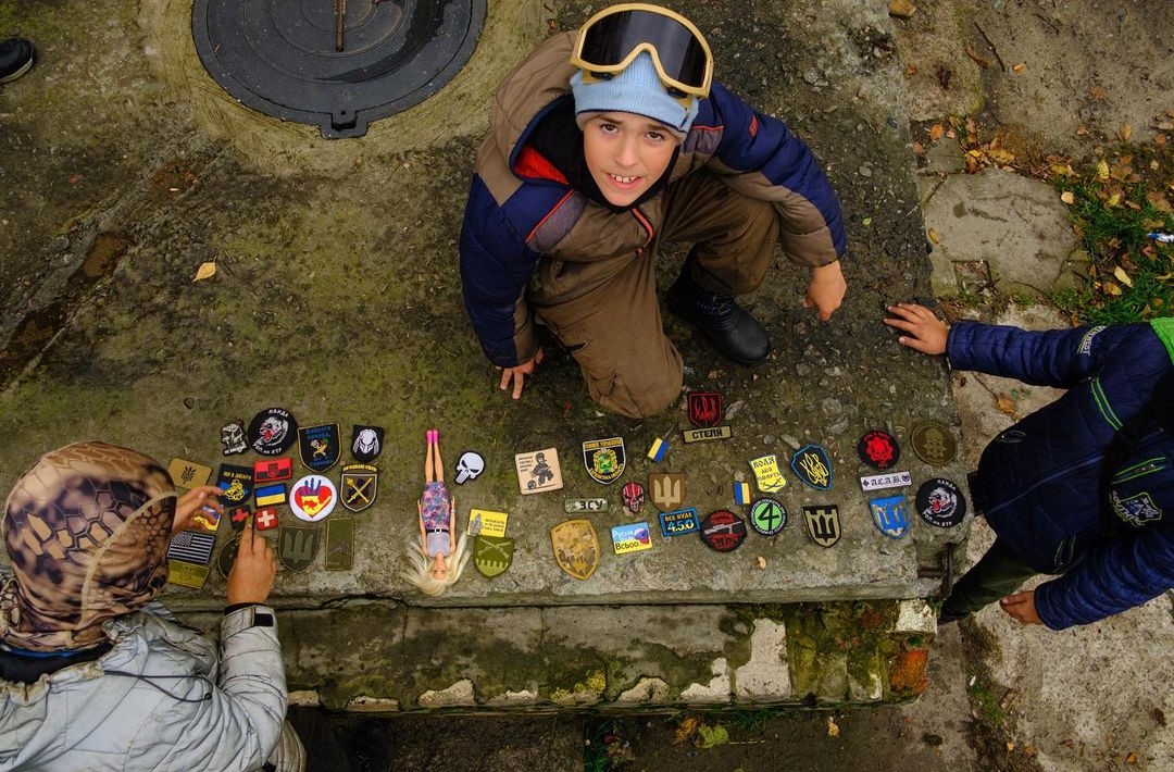 Мальчик Давид (тот, что в защитных очках) меняет военные шевроны на их с ребятами «блокпосте»